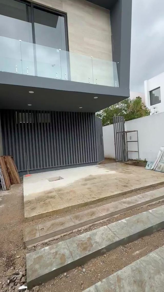 Fachada de vivienda con paneles oscuros, madera y barandal de cristal