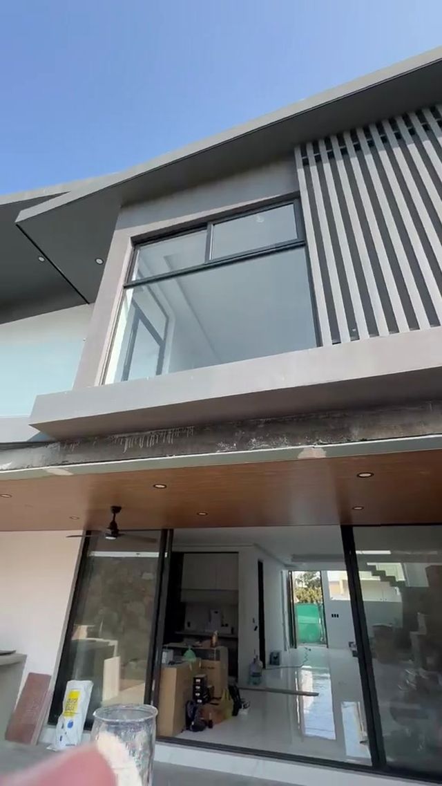 Fachada de dos niveles con soffit de madera y cristal corredizo