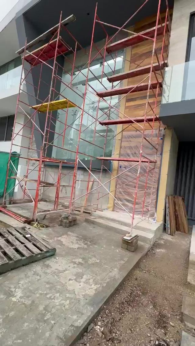 Fachada en obra con andamio y recubrimiento de madera