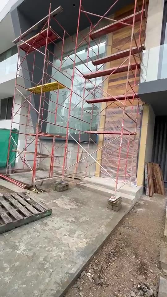 Fachada en obra con andamio y recubrimiento de madera